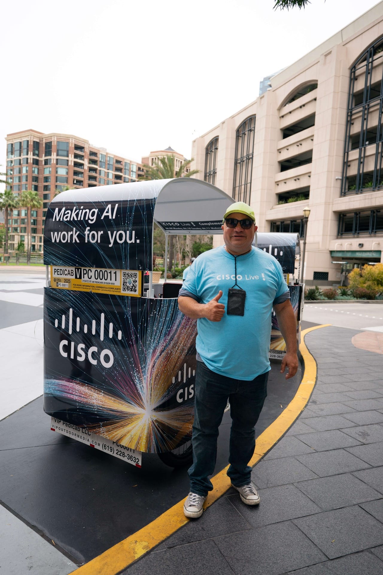 Cisco Live pedicab driver giving thumbs up next to branded wrap San Diego