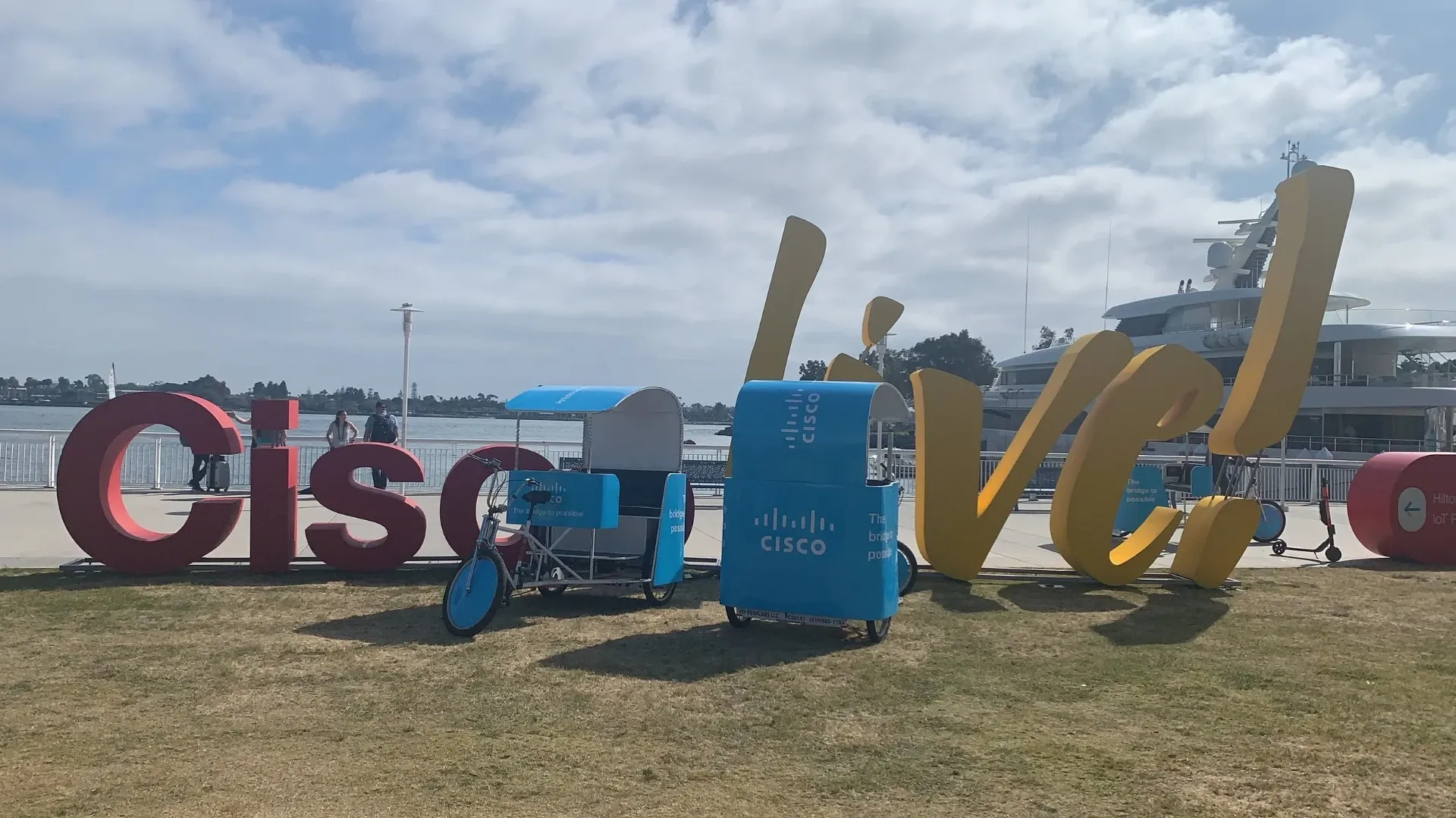 Cisco Live branded pedicabs next to giant sign sculpture on San Diego waterfront