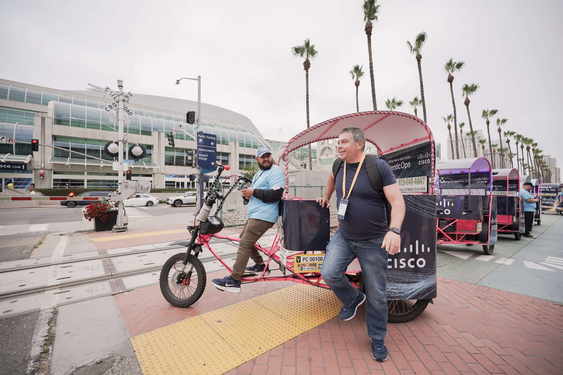 Cisco pedicab drivers chatting near pink branded bike at Convention Center