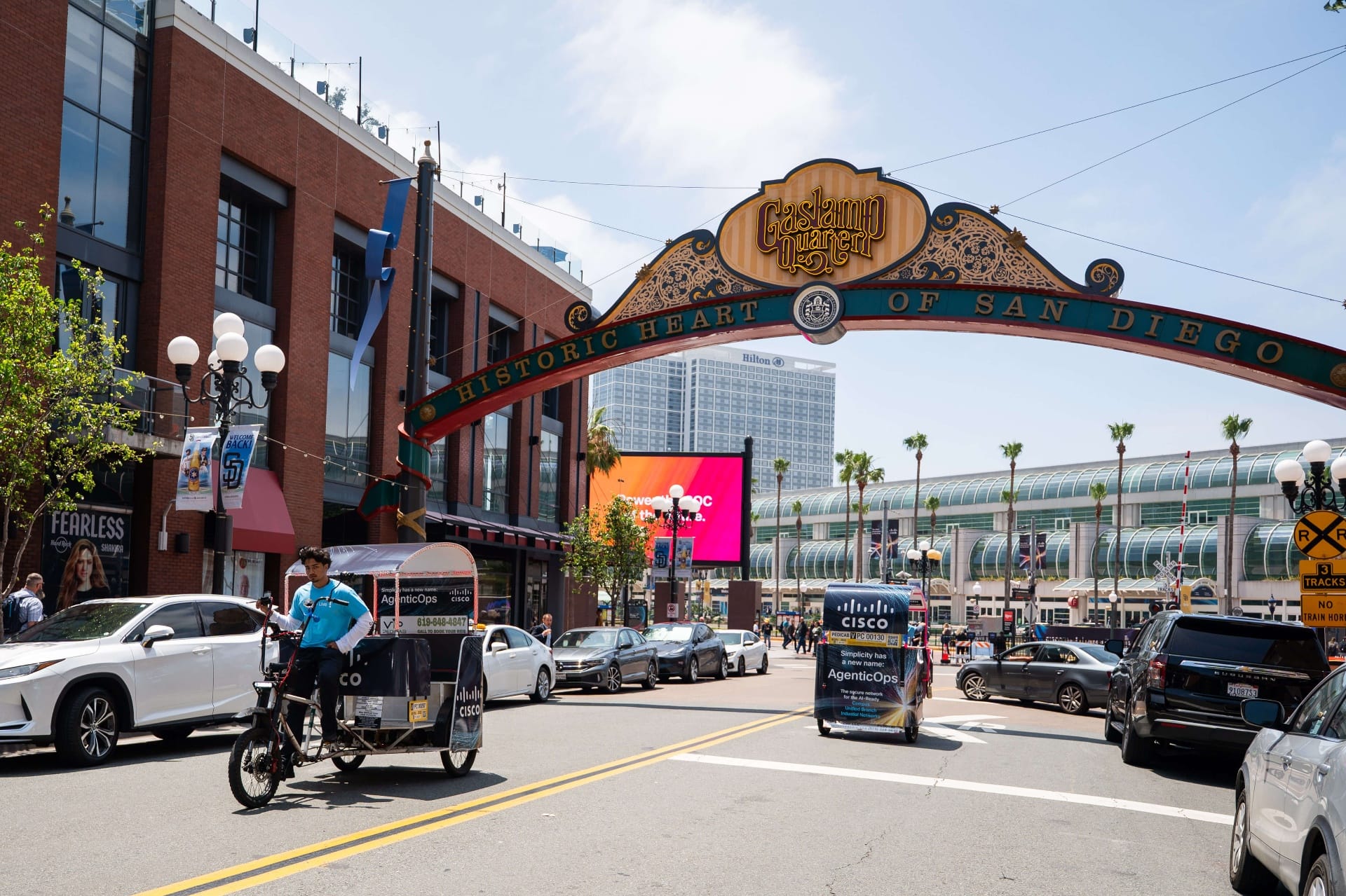 Cisco branded pedicab fleet riding under Gaslamp Quarter archway with Convention Center