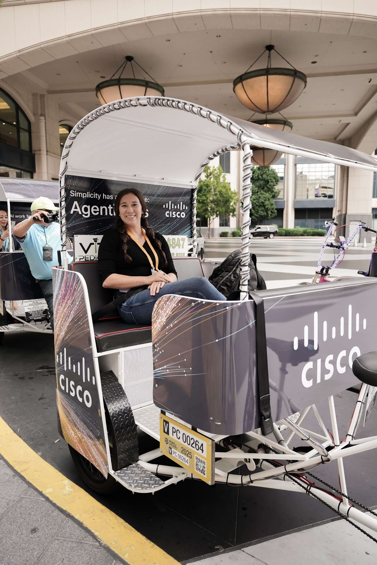 Smiling passenger in Cisco AgenticOps wrapped pedicab San Diego
