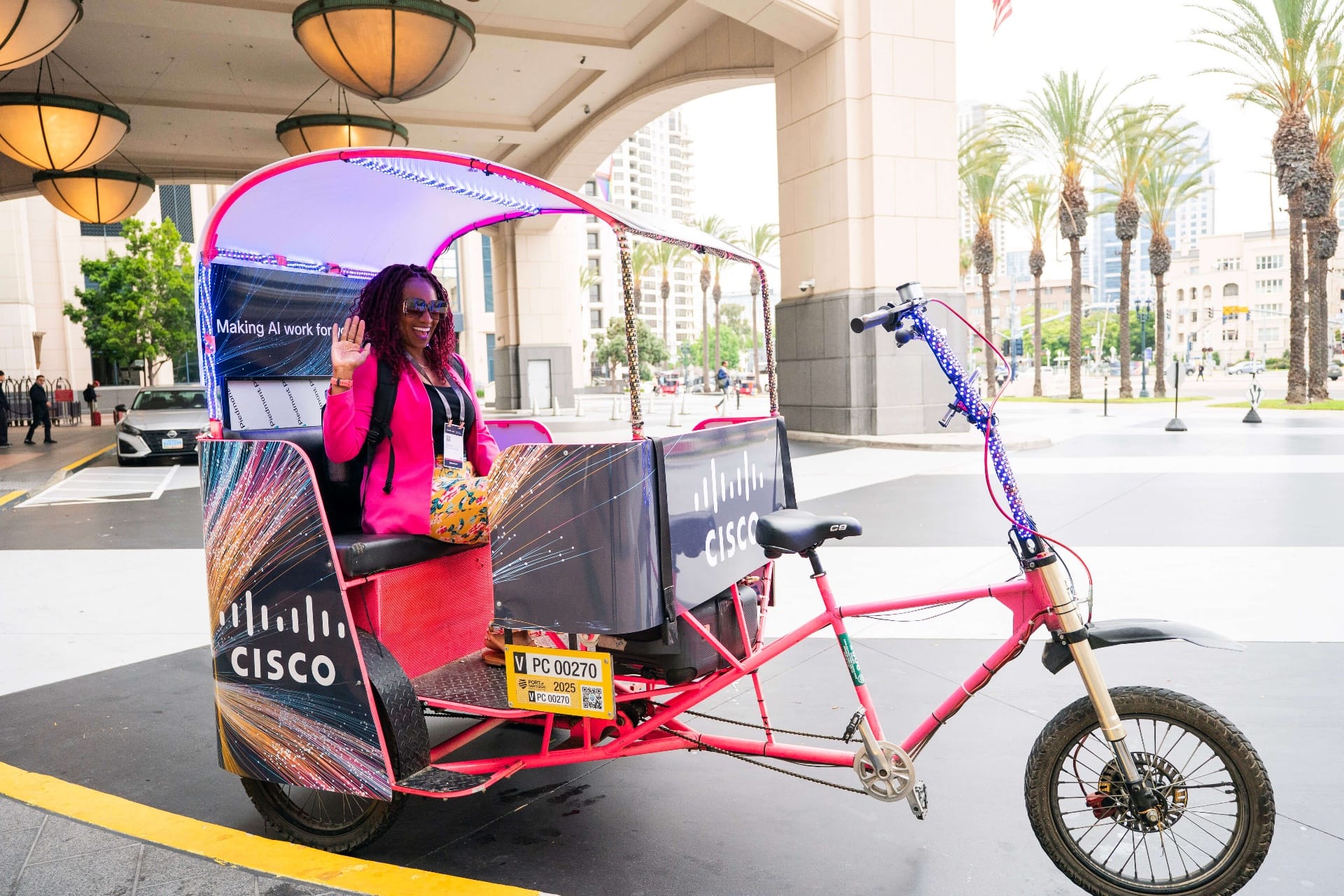 Passenger waving from pink Cisco branded pedicab San Diego