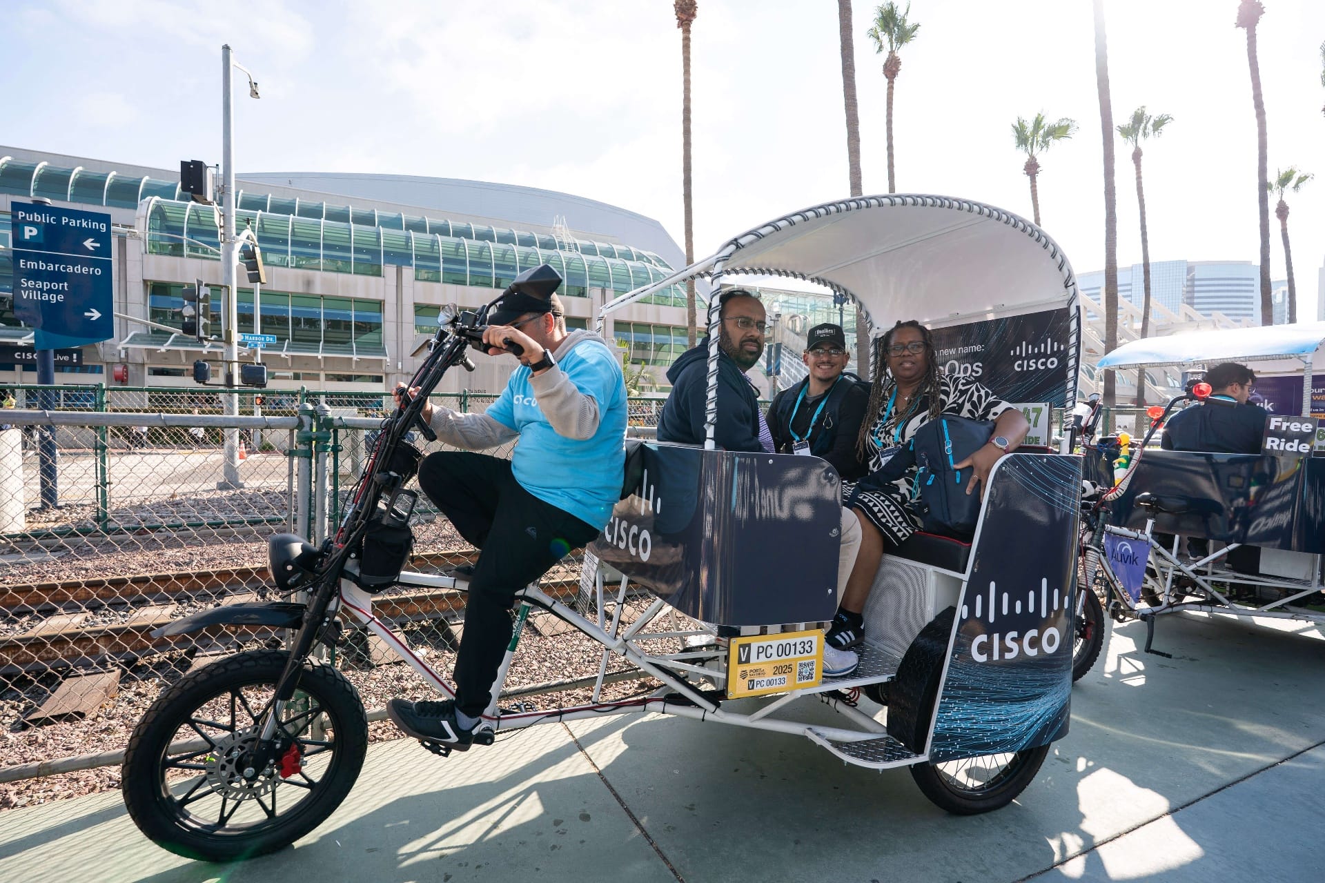 Smiling passengers in Cisco AgenticOps pedicab at downtown crossing