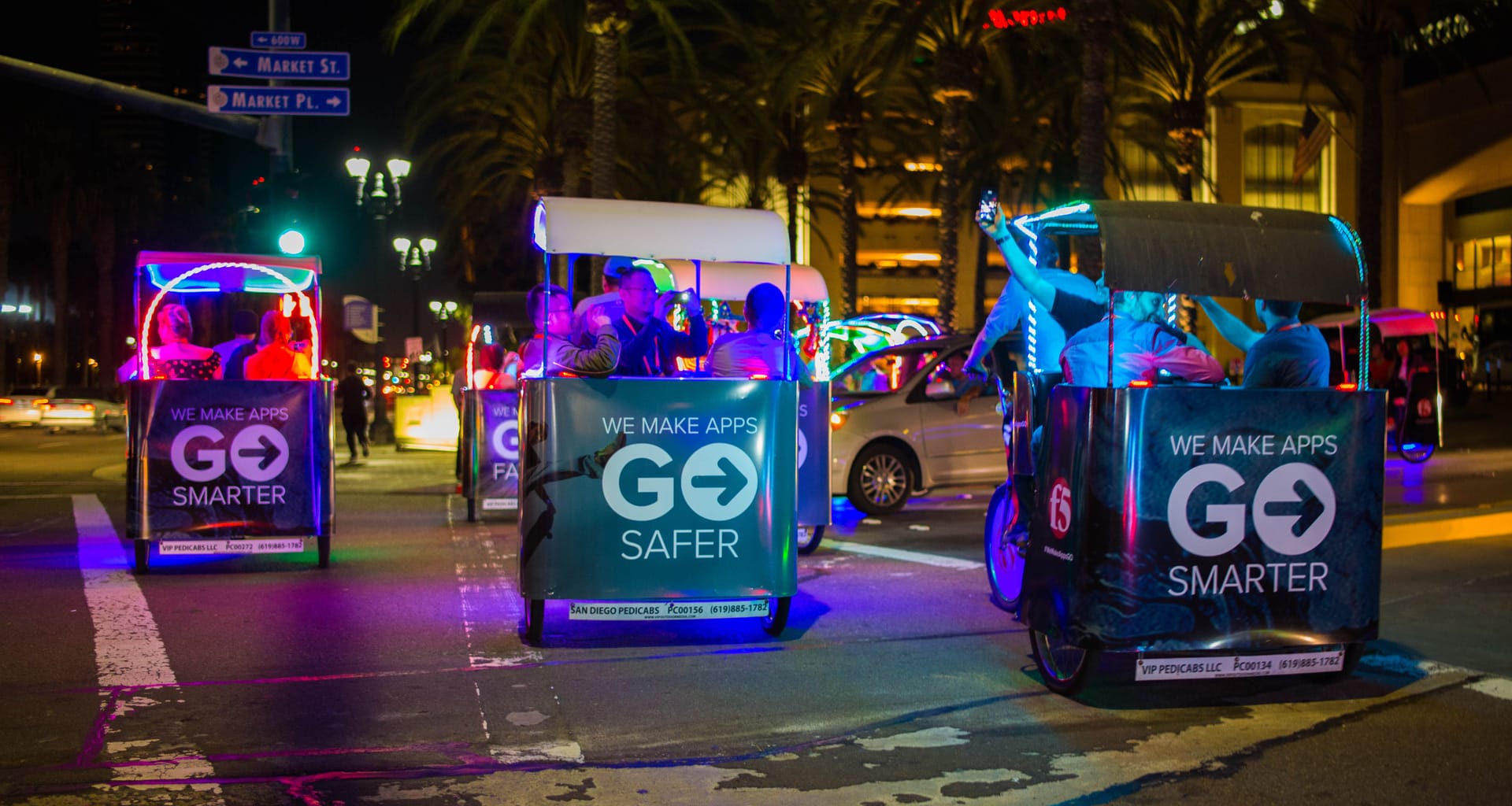 F5 branded LED pedicabs at night in downtown San Diego