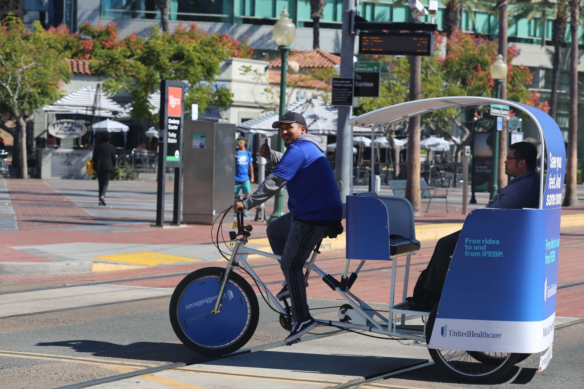 UnitedHealthcare pedicab driver giving thumbs up near Gaslamp trolley station