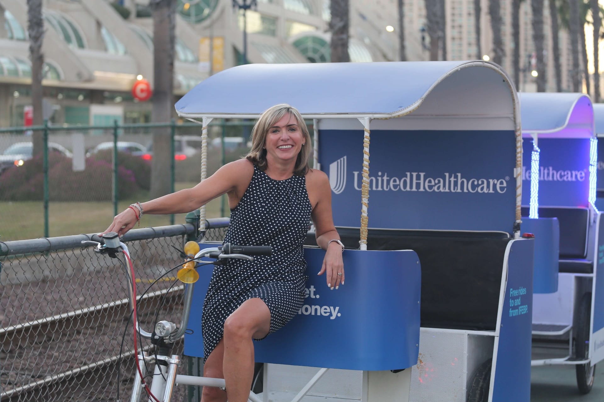 Guest portrait with UnitedHealthcare branded pedicab at evening convention