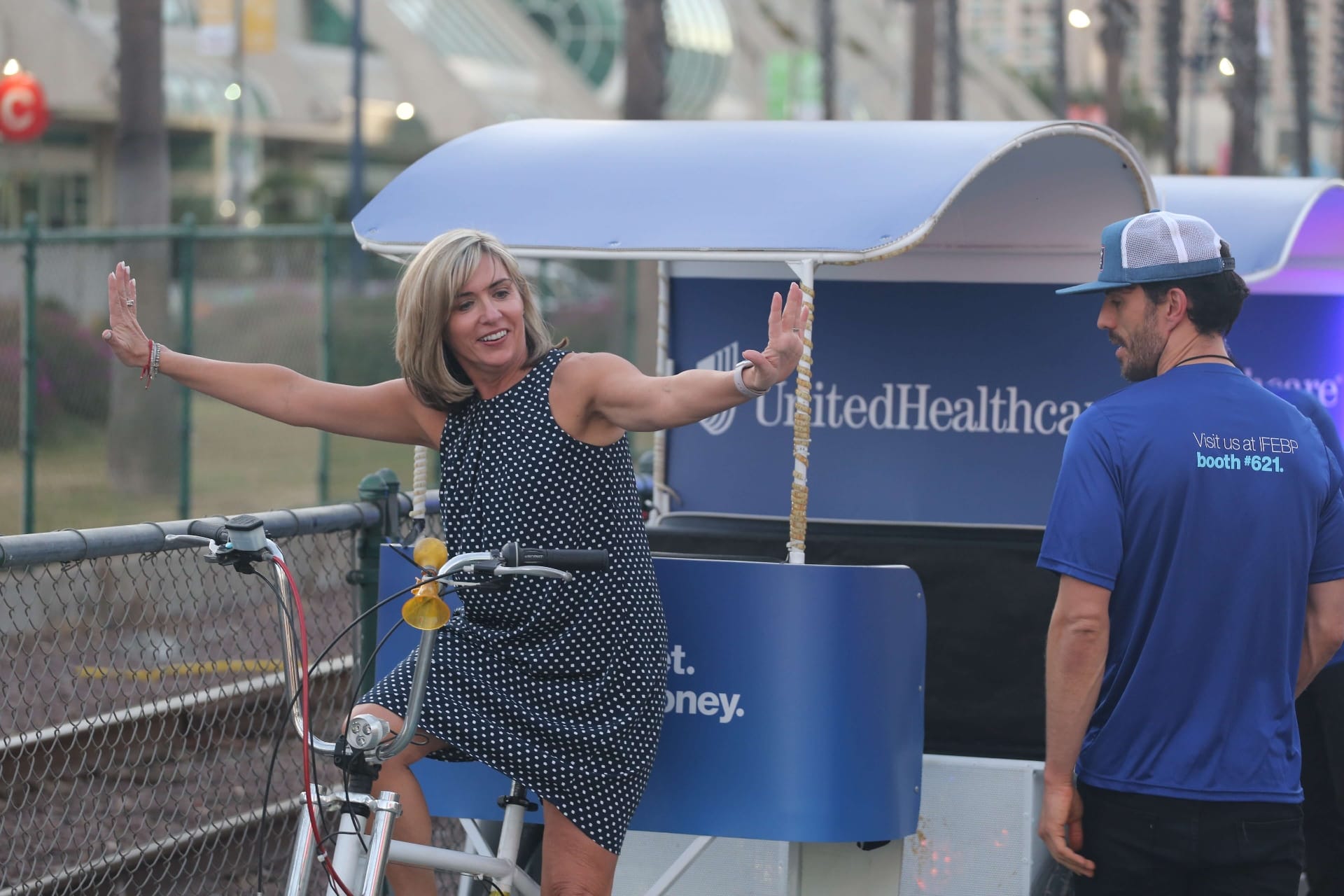 Happy guest posing with UnitedHealthcare pedicab at IFEBP convention