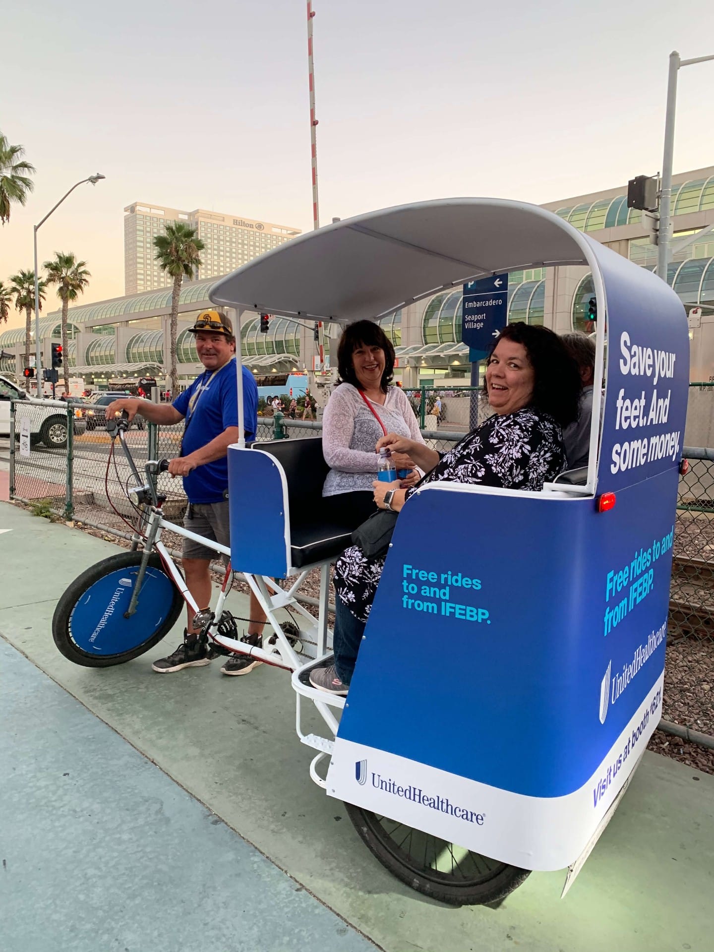 Happy passengers in UnitedHealthcare pedicab at Embarcadero San Diego